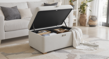 Stylish fabric storage ottoman in a modern living room, lid partially open showing organised storage inside.